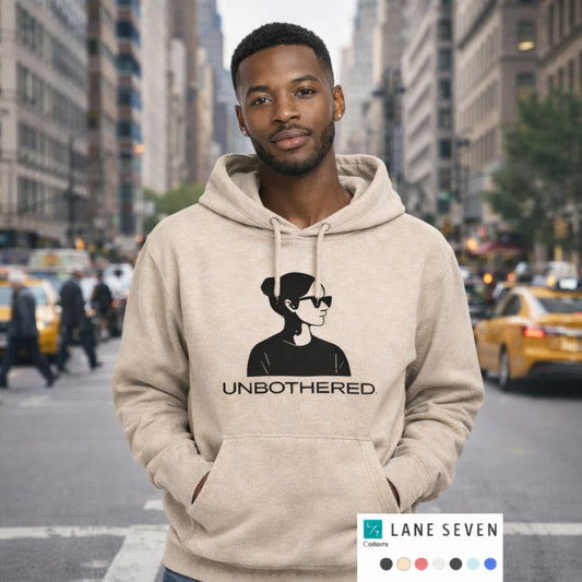 Man wearing a beige UNBOTHERED unisex pullover hoodie featuring a minimalist silhouette graphic, photographed on a city street with a modern urban backdrop.