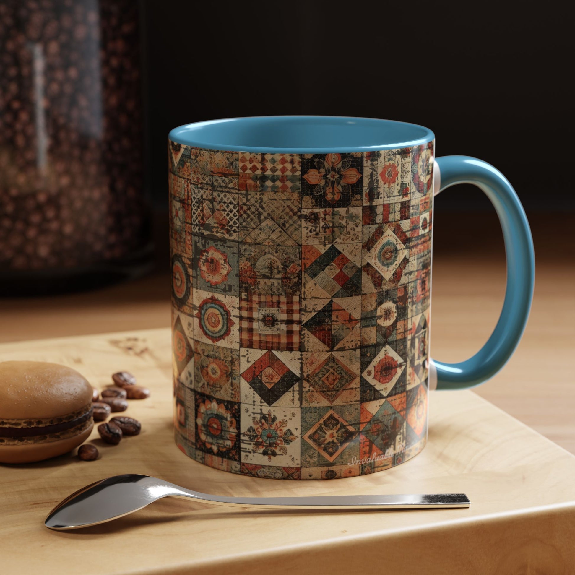 11oz Boho Patchwork Quilt mug with light blue accent handle — cozy coffee scene on wooden table with beans and macaron. Boutique boho drinkware by Invaluable Minutia. InvaluableMinutia.com